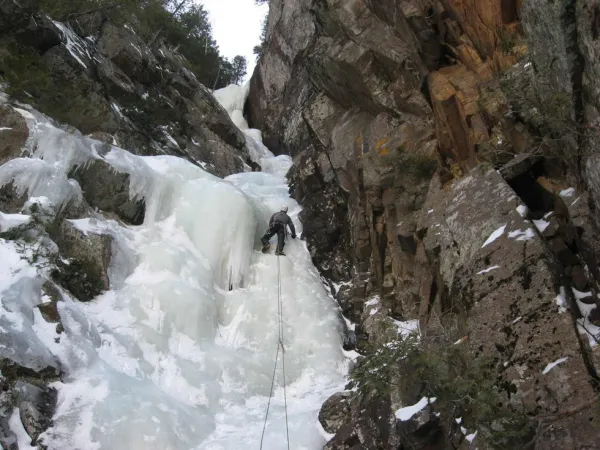 An ice climber going up a narrow flow