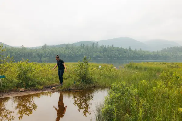 A hiker near the edge of a marshy area of water