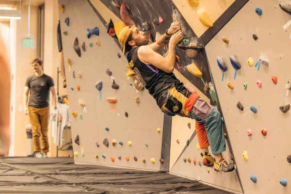 Climber holds onto climbing holds on an indoor bouldering wall just off the ground