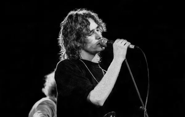 Black and white photo of Jeff Buckley singing into standing microphone