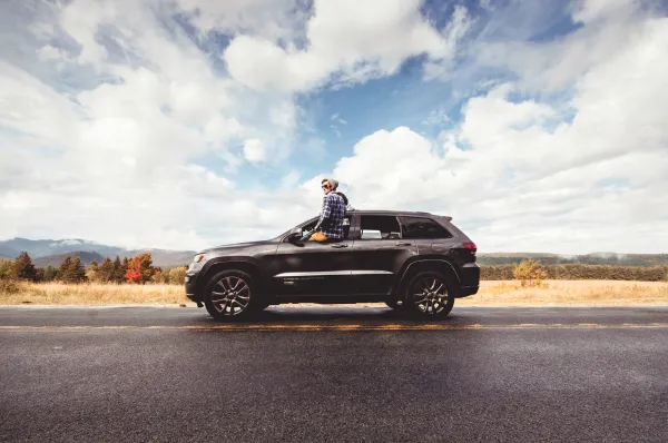 A man sits out of a car window. 