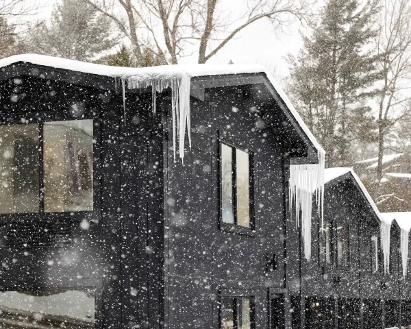 The black exterior of the building contrasting the icicles and freshly falling snow.