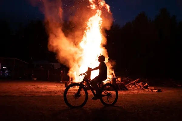 Bicyclist rides past a big bonfire
