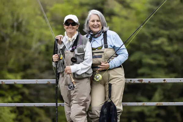 Two fisherwomen pose and smile holding poles