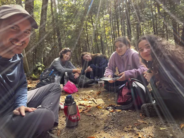 A group sits for a break with sunbeams shining through the trees