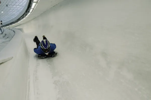 Person slides head first on a skeleton sled down an ice track