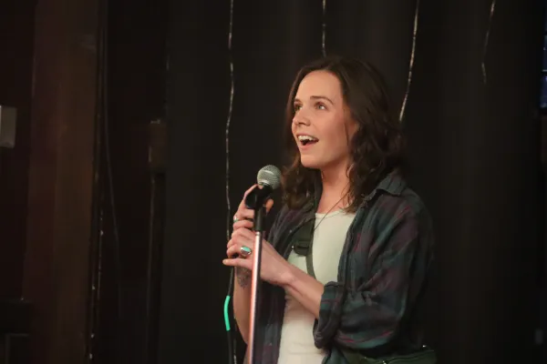Woman stands speaking into microphone on black draped stage