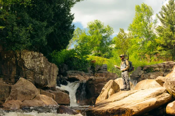 A flyfisher on some rocks by the water