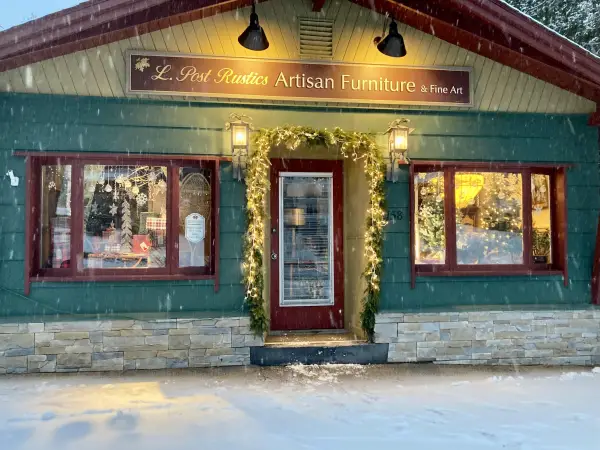 A gentle snow falls out front of the entry to L Post Rustics Artisan Furniture & Fine Art.