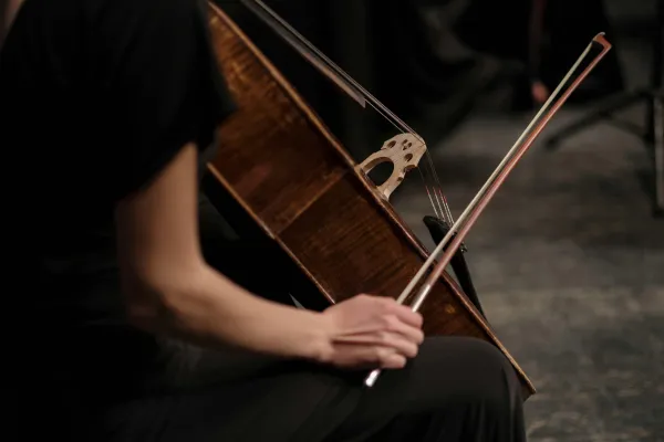 Stock image of woman in black dress sitting with cello holding bow