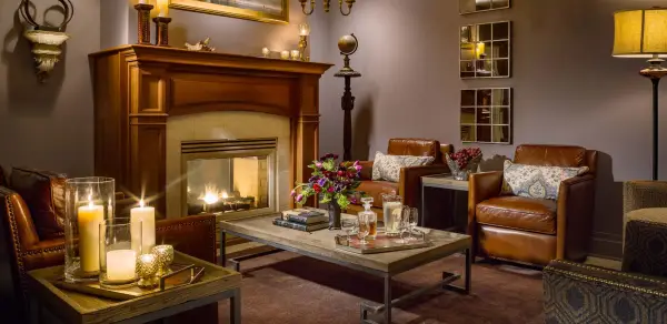 The cozy men's lounge with deep and dark leather chairs, candles, fireplace and warm ambiance