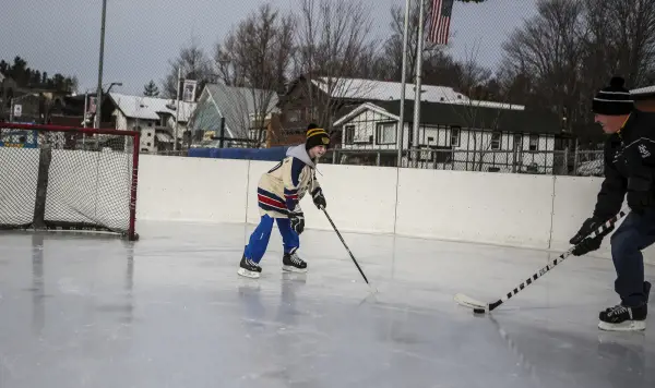 A father and son play hockey at a small rink