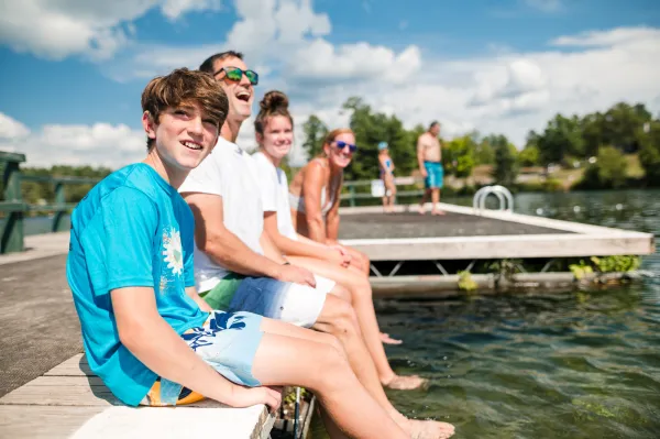A group of people sitting on a dock by a lake.