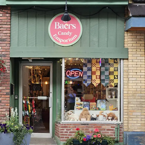 The exterior entry way of the candy emporium with green awning and pink circle emblem.