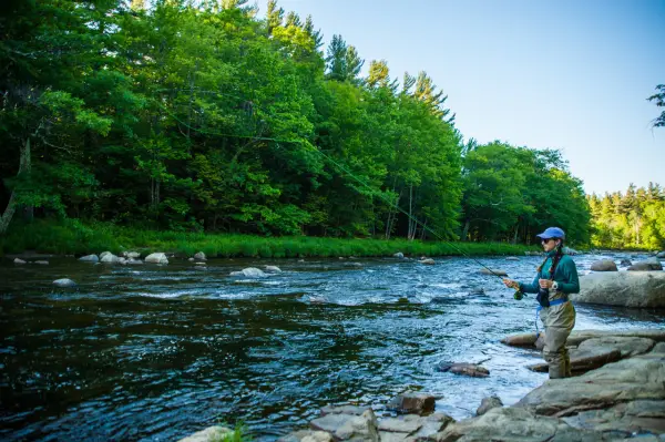 A young woman fishing the Au Sable River
