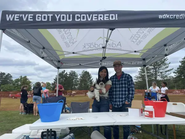 A couple holds a dog in a vendor tent at Bark in the Park