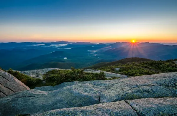 Sun rising over mountain range, seen from summit of another mountain