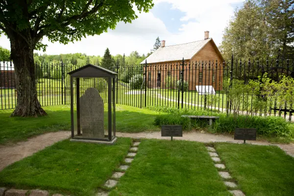 A wooden cabin and iron fence at a historical site