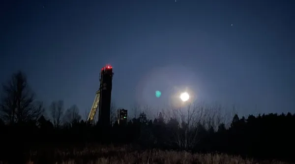 Full moon rising next to Olympic Ski Jumps at night