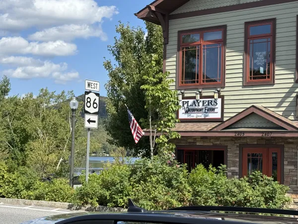 The exterior of Players Waterfront Eatery with Mirror Lake and the mountains in the background