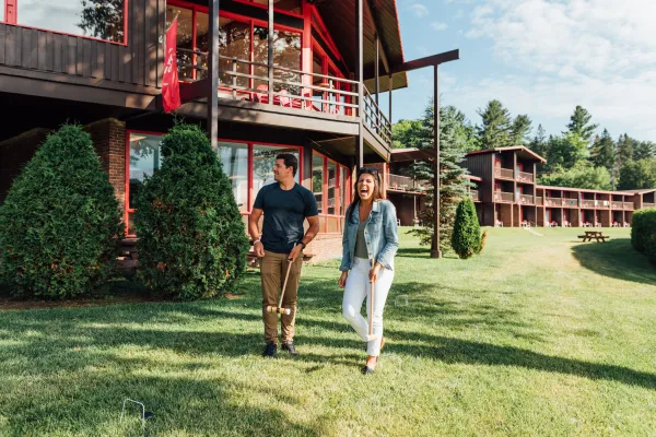 Couple walks on green lawn in front of brown and red lodge