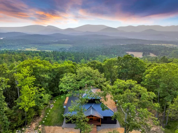 An aerial view of a new home with stunning view of the surrounding mountains and clouds.