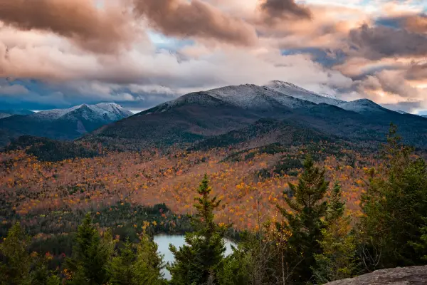 A pond and mountains with some snow on top during the late fall