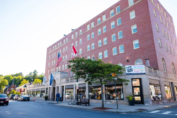 The exterior of Hotel Saranac, featuring an American flag and a Canadian flag flying near its stone-arched entrance.