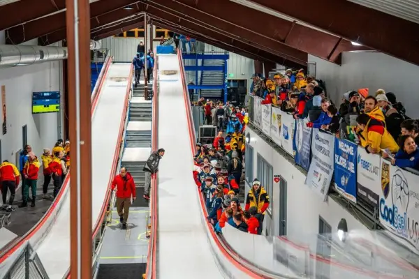 Indoor luge track with athletes and spectators.