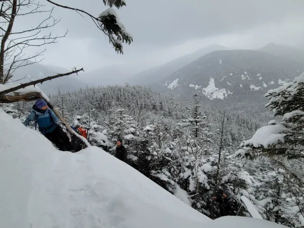 Winter hikers looking at a view from the top of a snowy cliff