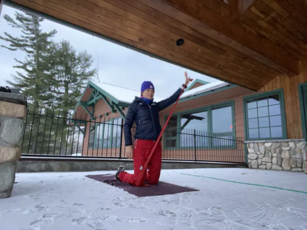 Person upside down doing yoga on a snowy deck outside a building.