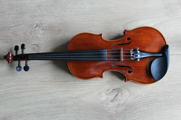 Stock image of a violin laying horizontally on a white wooden background