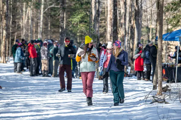 Two ladies walk down the trail with more brewski attendees behind them.