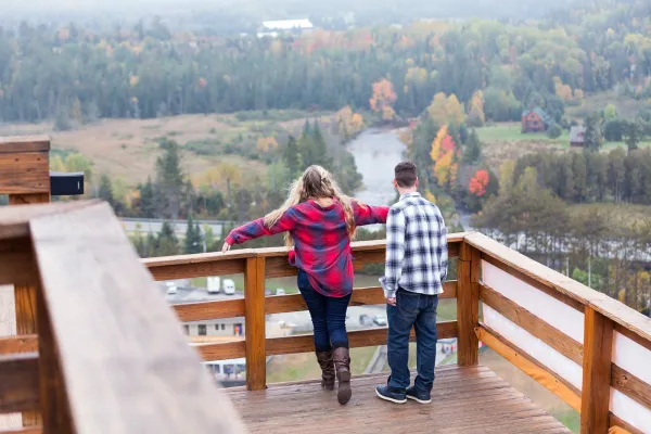 A man and woman overlook mountains from a balcony.