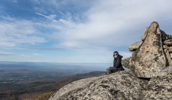 A hiker sits on the rocks on a summit