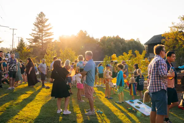 Families mingle on lawn at sunset 