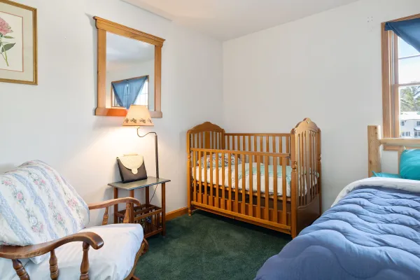 A wooden crib or toddler bed in the lower level bedroom at Lake Placid Pinehill Townhouse.
