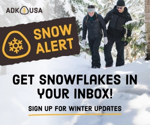 A man and woman walk through a snowy scene in a graphic for Snow alerts in Lake Placid. 