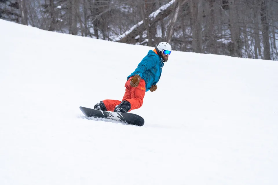 A man rides a snowboard across fresh powder on a ski mountain. 