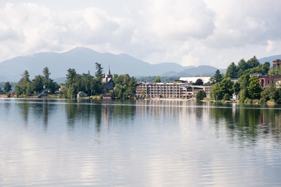 A hotel on clear water with mountains in the background.