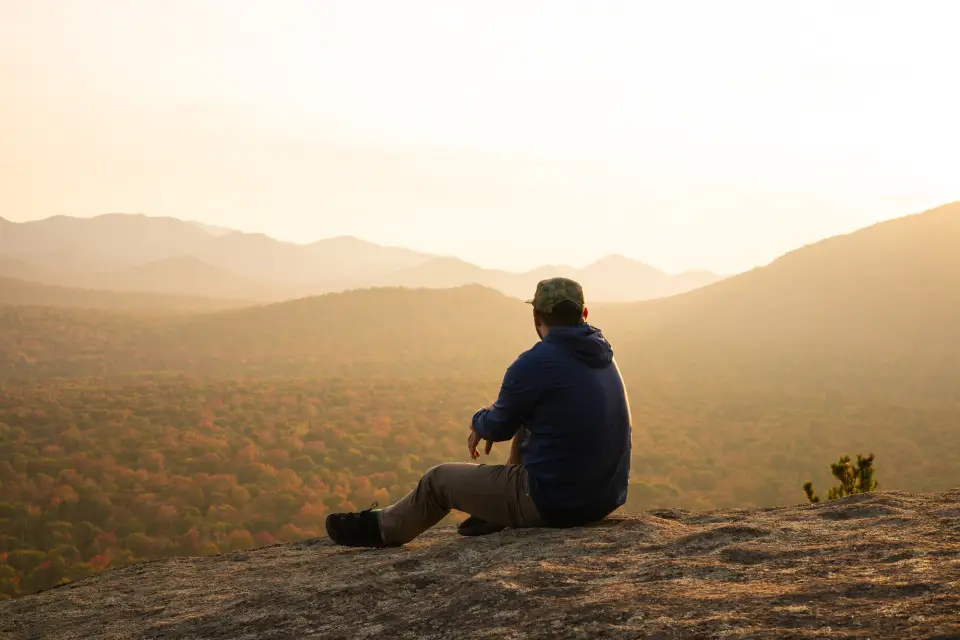 A man looks out to the mountains on a foggy day.