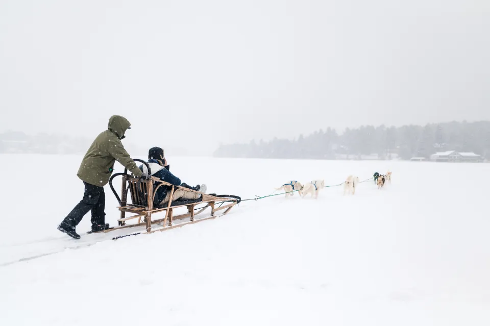 A couple riding a dog sled on Mirror Lake in Lake Placid.