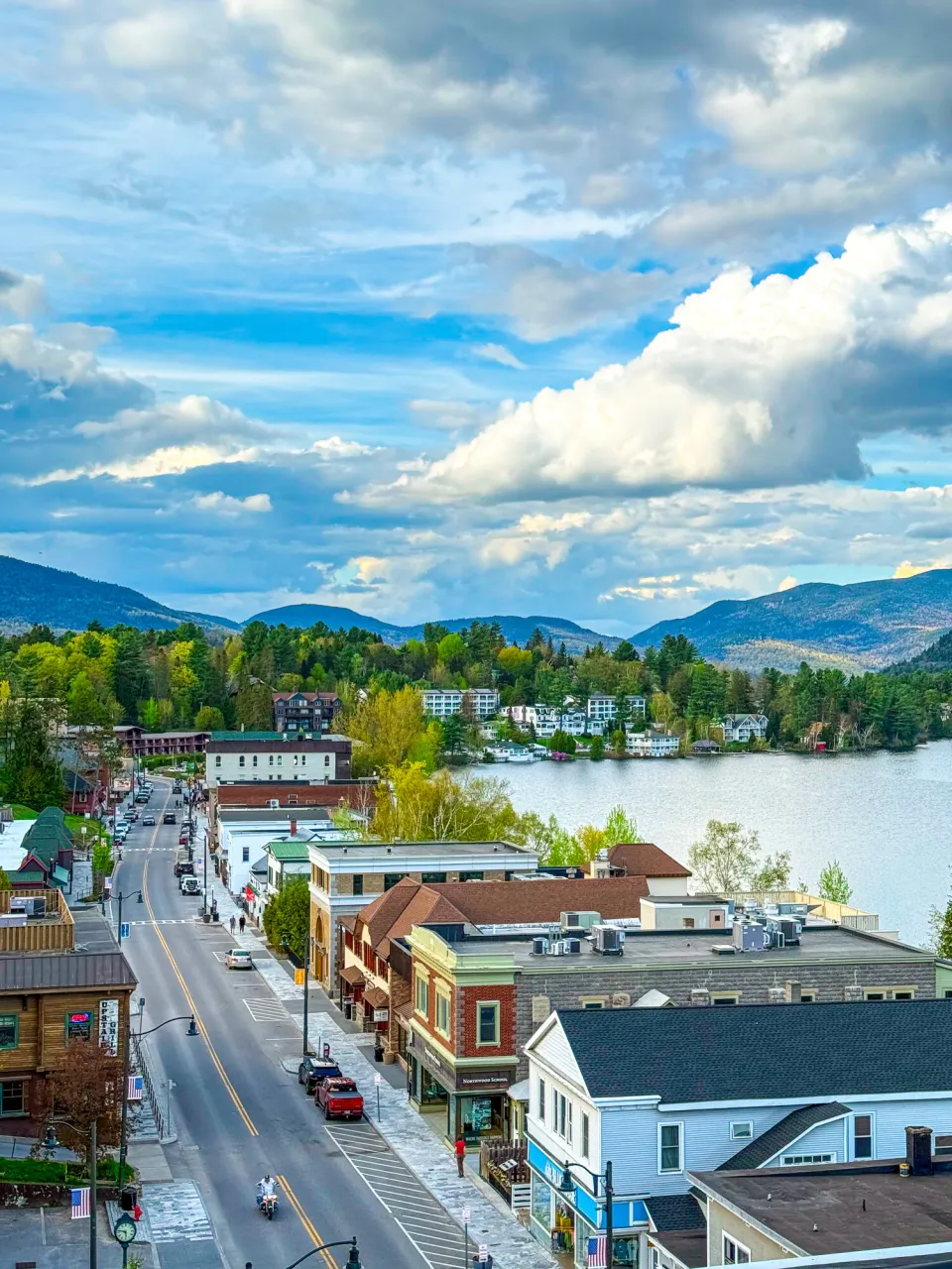 An aerial view of a mountain town main street nestled along a lake. 