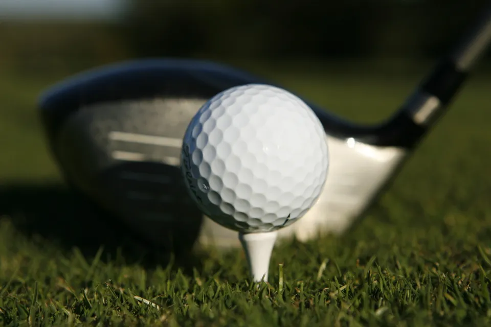 A close up of a person putting a golf ball.