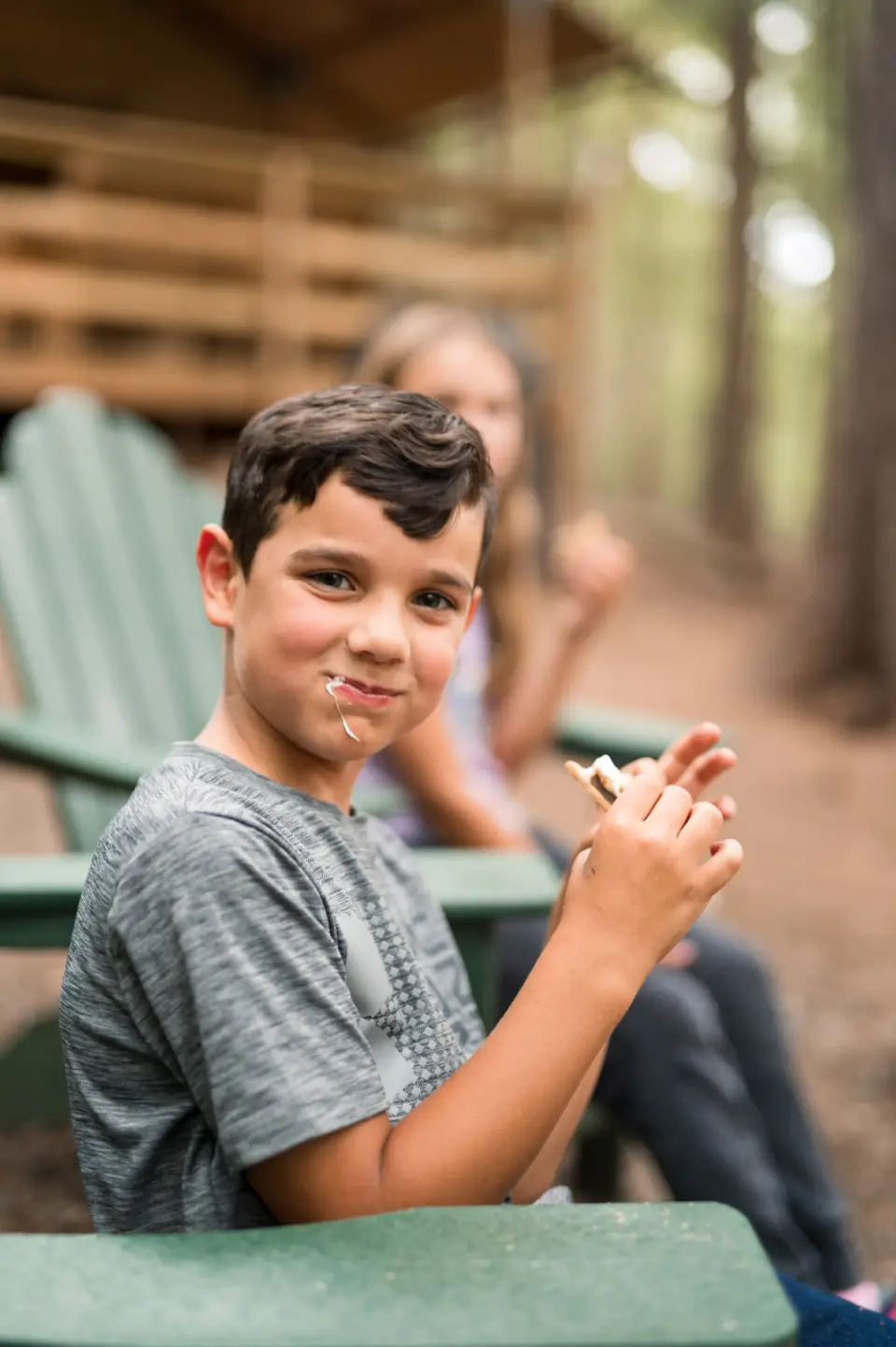 A child eats a s'more at a campsite.