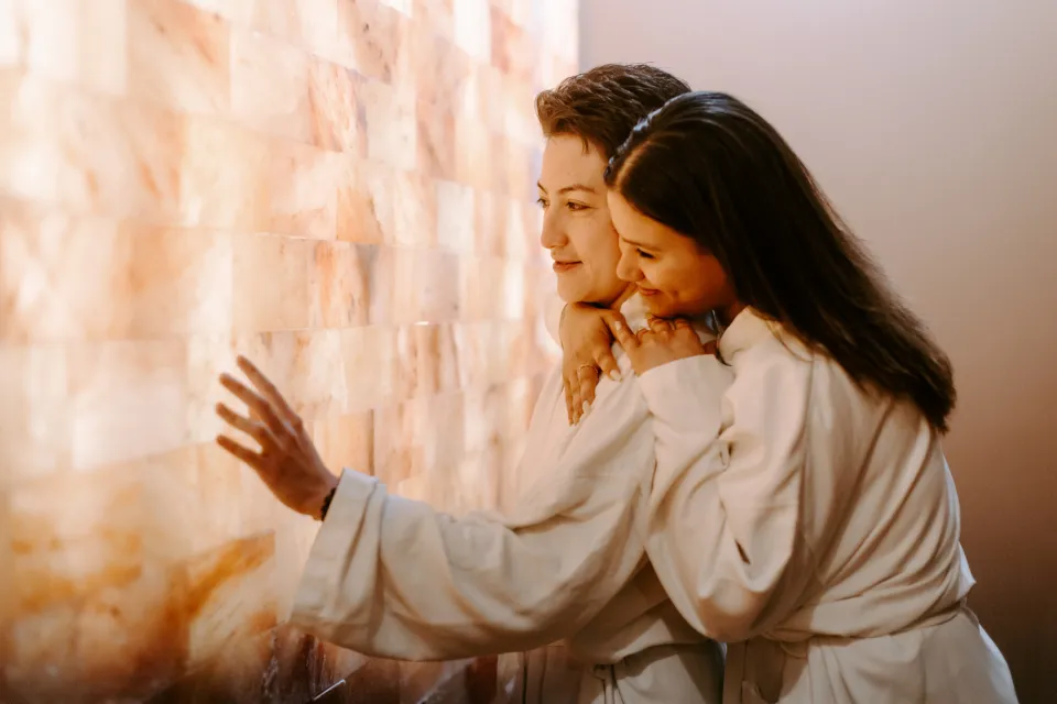 Two women embrace while in a salt room in a spa. 