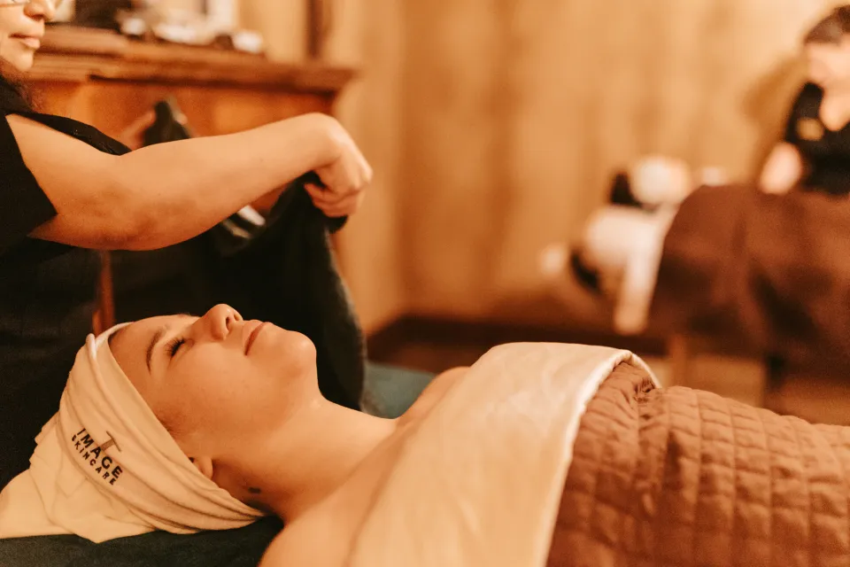 A woman lies on a massage table, covered in a towel.