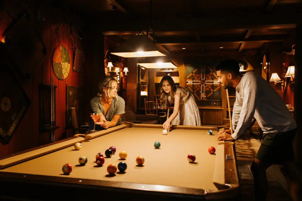 A group of friends play pool in a lodge.