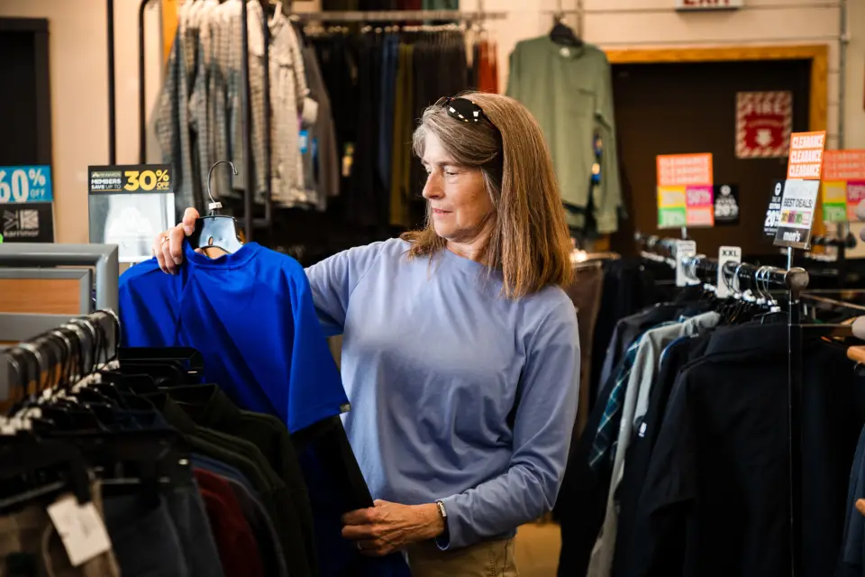 A woman peruses the clothing at a sporting goods/outfitters.