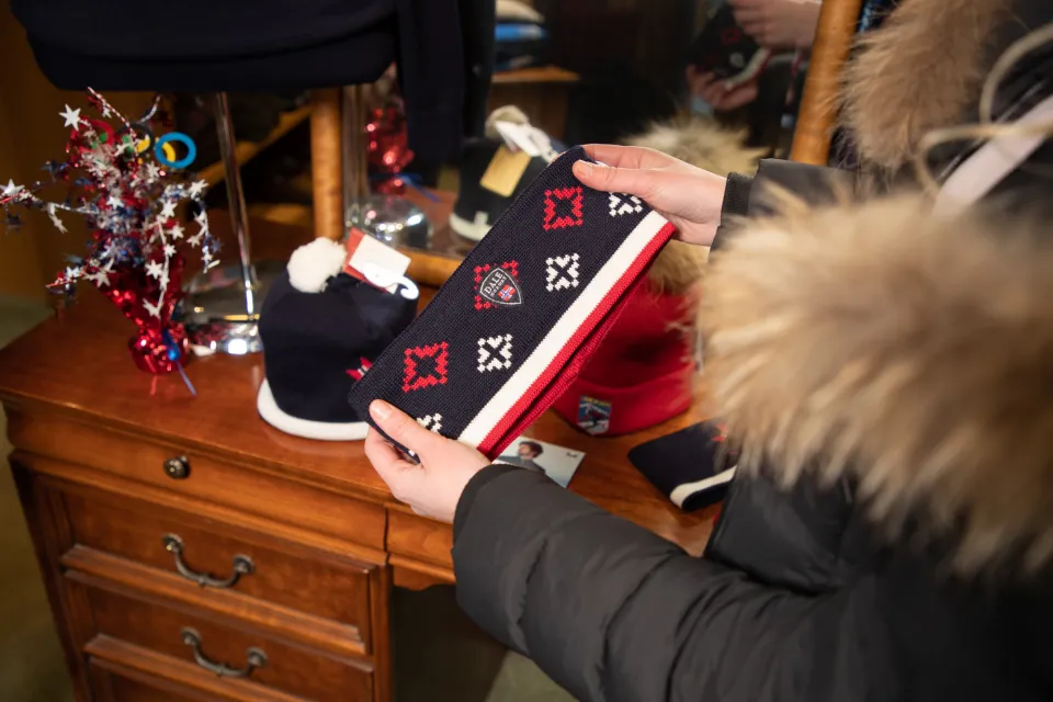 A close-up view of a woman holding a winter knitted headband in a shop.